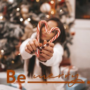 Girl smiling holding two candy canes in the shape of a heart.