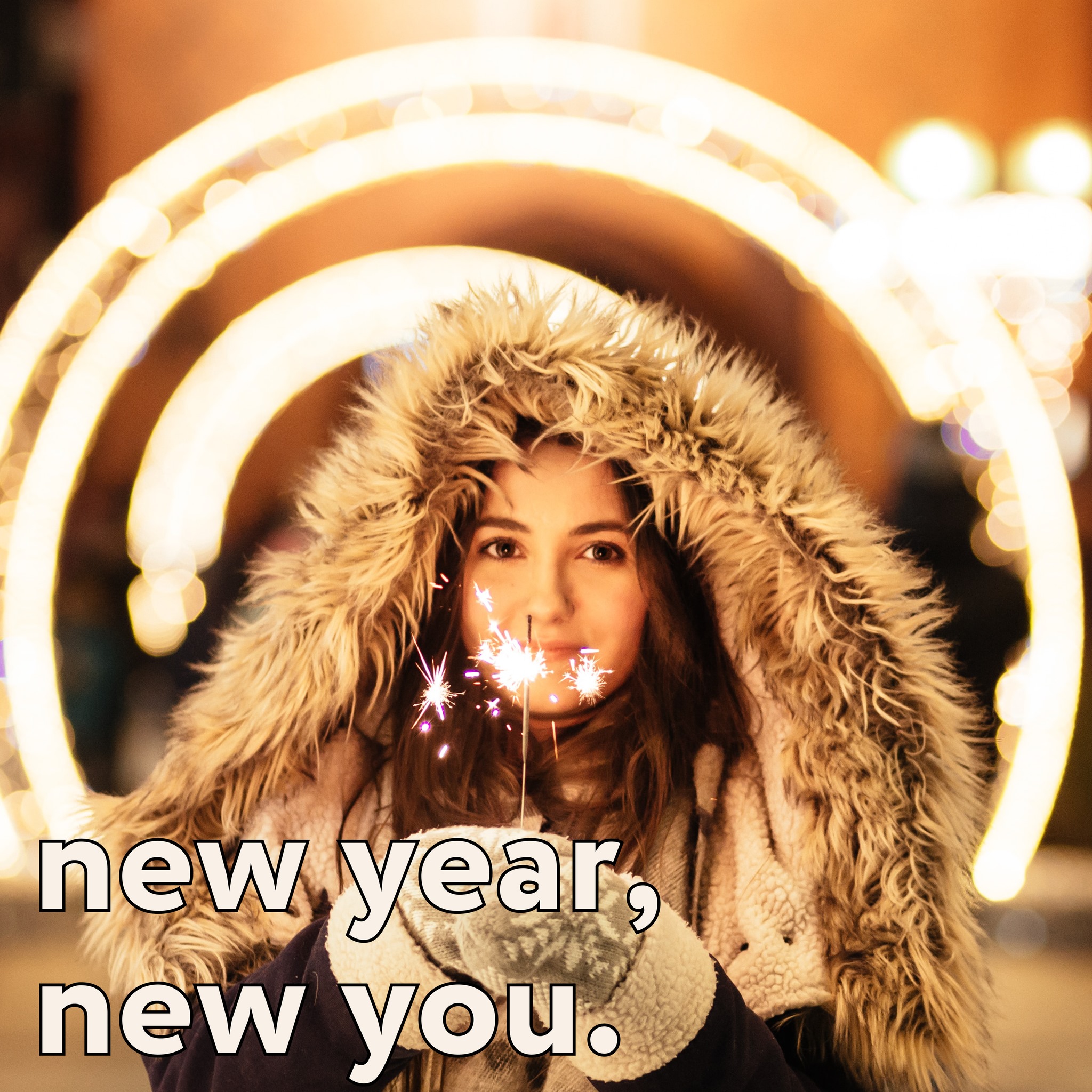 Girl with brown hair in fluffy coat holding sparklers