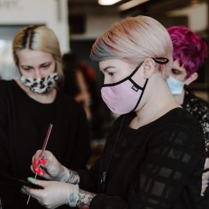 Cosmetology teacher styling client in chair to teach student.