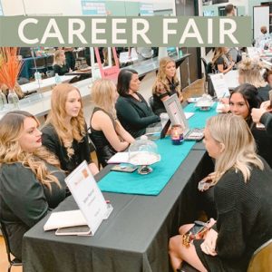Students sitting at a long table during a career fair.